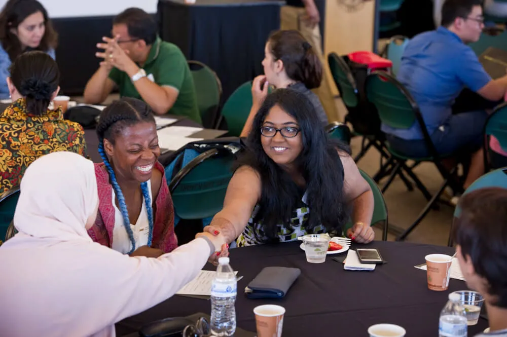 People around a table shaking hands at a conference.